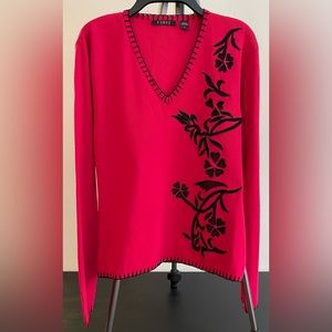 Women’s red knit top with black floral design.